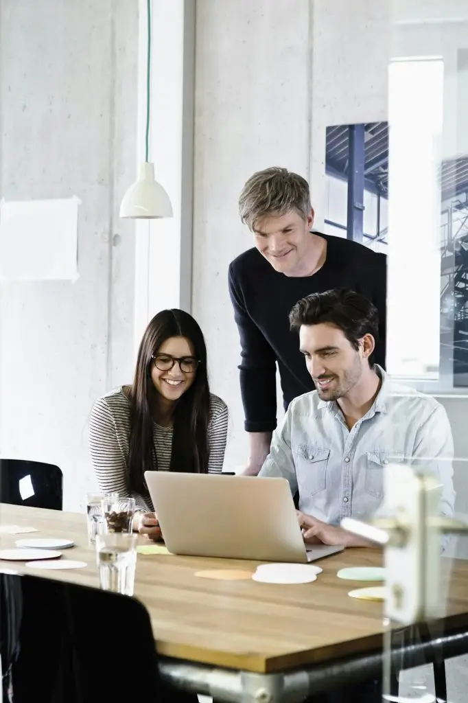 Colleagues in office using laptop smiling