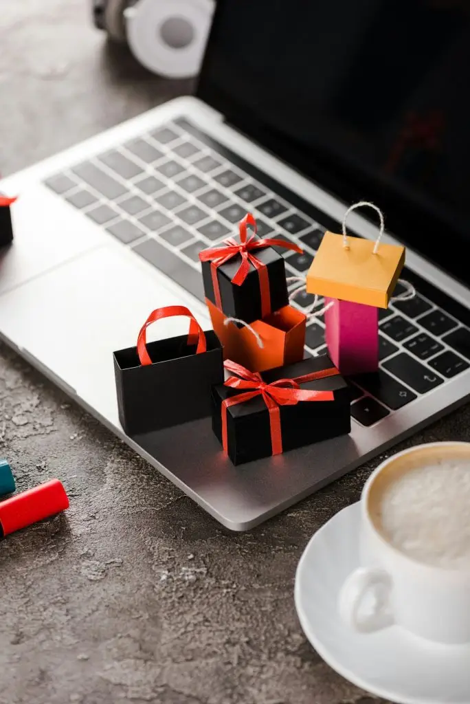 selective focus of shopping bags near laptop, cup of coffee and marker pens, e-commerce concept